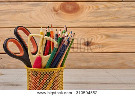 Colored Pencils And Scissors In Basket. Wood Color Pencils In Yellow Metal Pencil Holder. Stationery