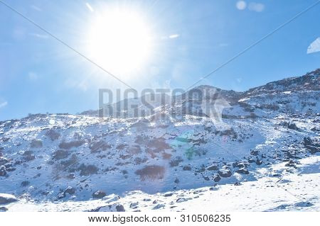 Sun On Top Of Snow Cover Himalaya Range. Frozen Rocky Peak Filled With Deep Snow Illuminate Rising S