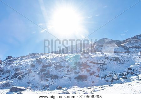 Sun On Top Of Snow Cover Himalaya Range. Frozen Rocky Peak Filled With Deep Snow Illuminate Rising S