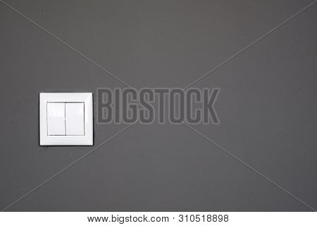 A Light Switch, A Plastic Mechanical Switch Of White Color Installed On A Dark Gray Wall. The Concep