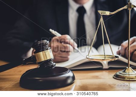 Male Lawyer Or Judge Working With Contract Papers, Law Book And Wooden Gavel On Table In Courtroom, 