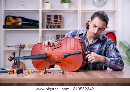 Young handsome repairman repairing violin