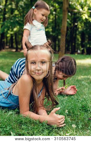 Three Funny Littlle Kids Playing On The Grass In Summer Park