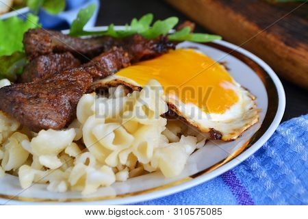 Steak Of Wild Boar With Egg And Pasta. Home Russian Cuisine