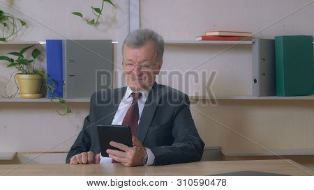 Handsome Retiree Man Holding Digital Tablet Using App For Call. Greyhead Male Wearing Suit Talking V