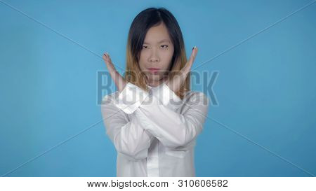 Young Asian Woman Posing Showing Hand Gesture Stopping Refuse On Blue Background In Studio. Attracti