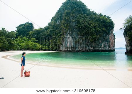 Woman Standing On The Beach Looking At The Sea With Beachbag On Vacation.
