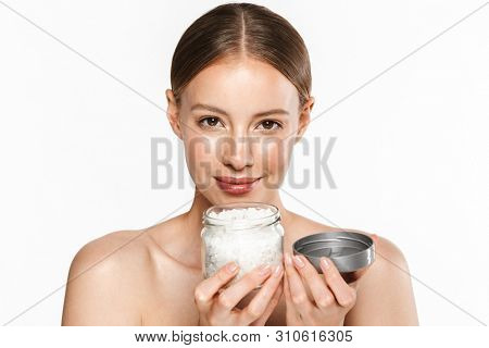 Image of young half-naked woman holding bath salt jar and looking at camera isolated over white background