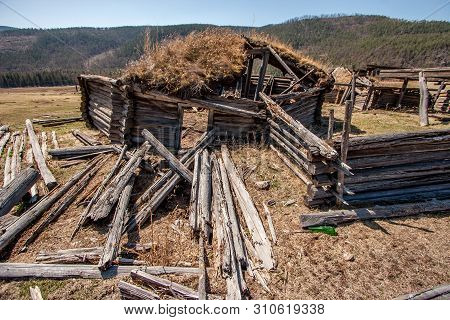 Old Wooden Ruined Yurt. Close-up. In The Foreground Rotten Logs. Rotten Fence.