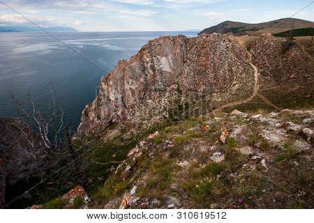 A Large Rock On The Shore Of Lake Baikal. There Is A Path To The Rock. There Is A Dry Tree. Behind A