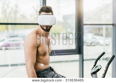 Shirtless Sportsman In Virtual Reality Headset With Electrodes Working Out On Elliptical During Endu