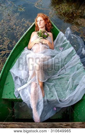 Beautiful Young Abandoned Woman, Bride, Lady Of Shalott, Lies Eagerly Abandoned With A Bouquet Of Fl