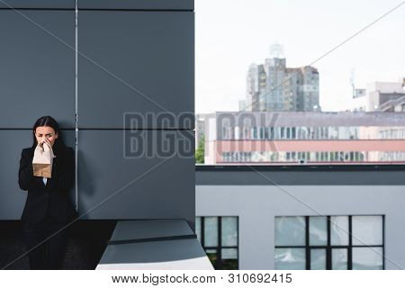 Young Businesswoman, Suffering From Panic Attack, Standing On Rooftop And Breathing Into Paper Bag