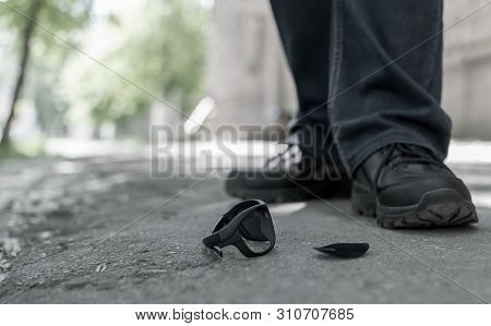 View Of The Feet Of A Man Who Stands On An Asphalt Road On The Background Of Fallen And Broken Sun G
