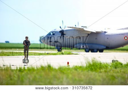 Boboc, Romania - May 22, 2019: Romanian Army Soldier Patrols A Military Air Base, With An Alenia C-2