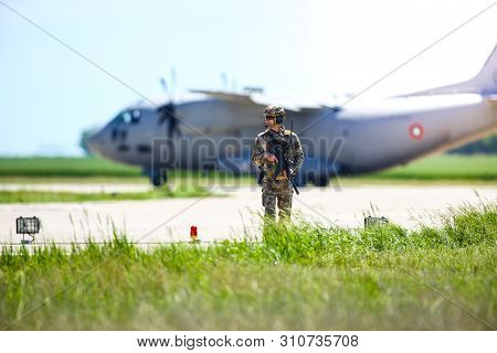 Boboc, Romania - May 22, 2019: Romanian Army Soldier Patrols A Military Air Base, With An Alenia C-2