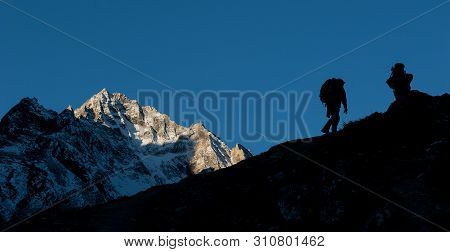 Young Woman And Man With Backpacks Walking To The Pass On Manaslu Circuit With View Of Mount Manaslu