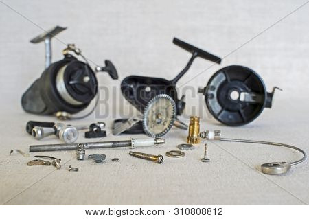 A Fishing Spinning Reel As A Whole And A Second Similar Completely Disassembled. Concept: Parts Of A