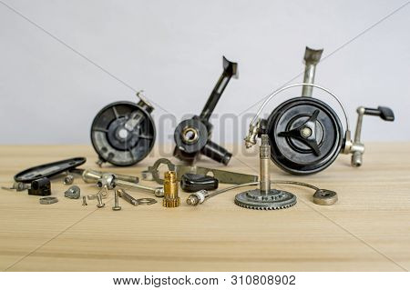 A Fishing Spinning Reel As A Whole And A Second Similar Completely Disassembled. Concept: Parts Of A
