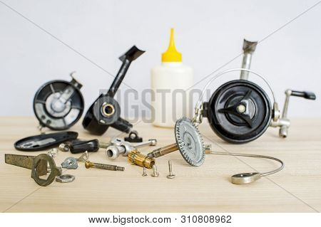 A Fishing Spinning Reel As A Whole And A Second Similar Completely Disassembled. Concept: Parts Of A