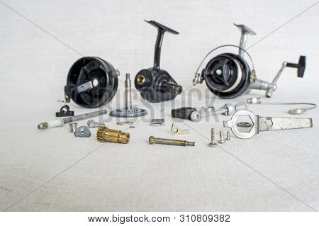 A Fishing Spinning Reel As A Whole And A Second Similar Completely Disassembled. Concept: Parts Of A