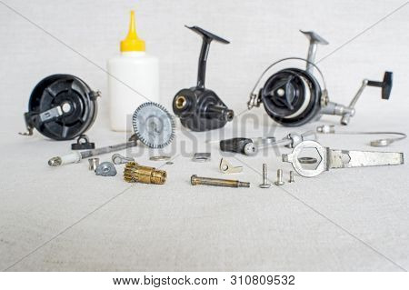 A Fishing Spinning Reel As A Whole And A Second Similar Completely Disassembled. Concept: Parts Of A