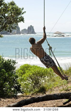 Homme corde swing à la plage