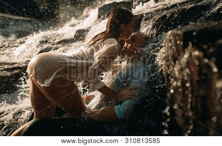 A Couple In Love During Lovemaking Under The Streams Of A Waterfall.