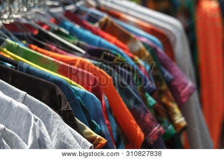 Close-up Of Multi-colored T-shirts Hanging On Hangers In The Street, Fair, Secondhand, Recycling Con
