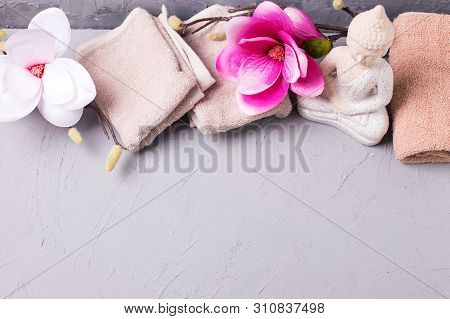View From Above On Decorative Buddha And Pink Magnolia Flowers And  Towels  On Grey Textured Backgro