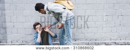 Panoramic Shot Of Aggressive And Brunette African American Boy Bulling Frightened Boy In Glasses