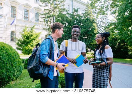 Laughing African American Female Student With Backpack With Two Males Multiethnic Friends Talking Ou