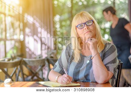 Portrait Of Beautiful Plus Size Middle Age Woman Working And Making Notes To Her Diary On Sunny Terr