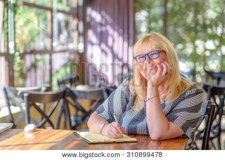 Portrait Of Beautiful Plus Size Middle Age Woman Working And Making Notes To Her Diary. Elegant Midd