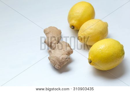 Three Yellow Lemons And Ginger Root On A Light Background.
