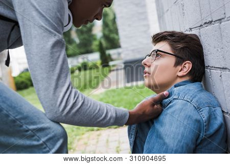 Aggressive And Brunette African American Boy Bulling Scared Boy In Glasses