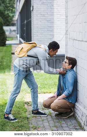 Aggressive And Brunette African American Boy Bulling Scared Boy In Glasses