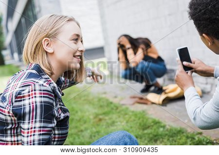 African American Boy And Blonde Teenager Pointing With Finger And Shooting Scared Teenager