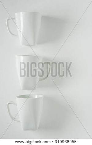 3 White Coffee Mugs On White Background In A Vertical Row, Empty Copy Space