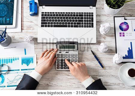 Businessman Using Calculator At Wooden Desk. Financial Audit And Finance Accounting. Top View Office