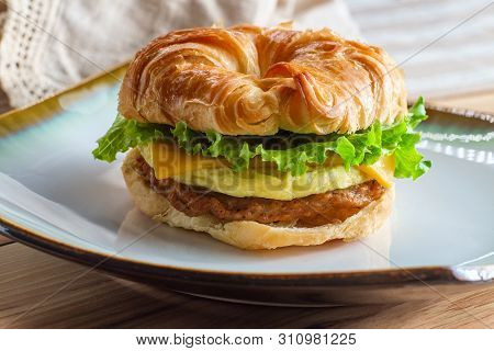 Sausage Egg And Cheese On Flaky French Croissant Roll With Romaine Lettuce