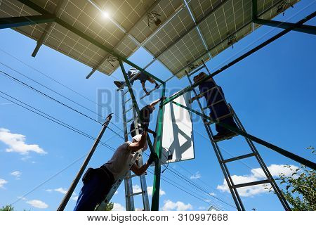 Two Mounters Installing Solar Batteries On Metallic Carcass. Innovative Solution For Natural Resourc