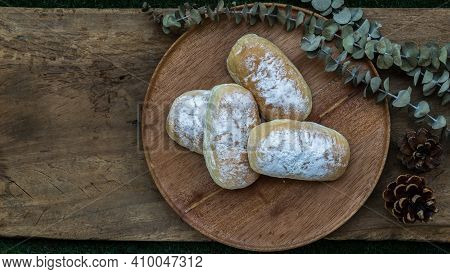 Four Homemade Sweet Cream Soft Buns And Sprinkled With Icing Sugar On Round Wooden Plate Over Rustic