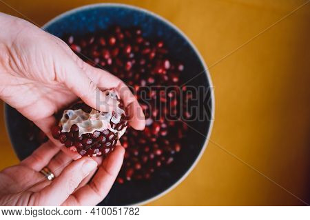 Womans Hands Deseeding Fresh Red Pomegranate Close Up Background. Healthy Eating Concept.