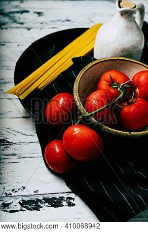 Uncooked Spaghetti,  Organic Tomatoes And Jug Of Olive Oil