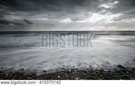 Seawaves Splashing To The Coast With Pebbles Against Stormy Dramatic Cloudy Sky. Wintertime, Longexp
