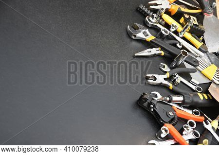 Handyman Tool Kit On Black Wooden Table. Many Wrenches And Screwdrivers, Pilers And Other Tools For 