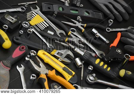 Handyman Tool Kit On Black Wooden Table. Many Wrenches And Screwdrivers, Pilers And Other Tools For 