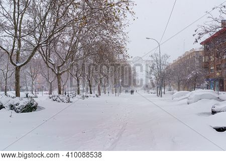 Streets And Buildings Covered In Snow By Day Due To Snowstorm Filomena Falling In Madrid Spain. Peop
