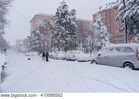 Streets And Buildings Covered In Snow By Day Due To Snowstorm Filomena Falling In Madrid Spain. Peop